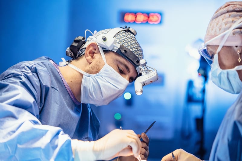 Le Dr Frédéric Lange en intervention — chirurgie du nez sous loupes et éclairage frontal